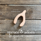 organic, one-of-a-kind, wooden wishbone shaped teether with cotton ball scarf overlying a wooden background with store logo