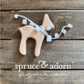 organic, one-of-a-kind, wooden deer shaped teether with cotton ball scarf overlying a wooden background with store logo