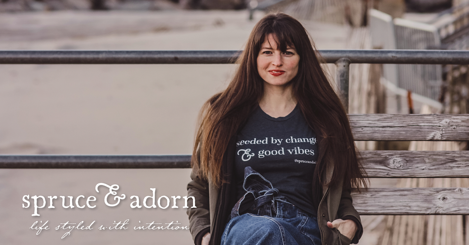 Harpist Christine Elise, one half of the neo-soul music duo Kuf Knotz, rests comfortably beachside on a driftwood bench, wearing her cotton “seeded by change & good vibes” crew neck t-shirt. + positive affirmation apparel. On the go — life styled with intention™ at spruce & adorn™