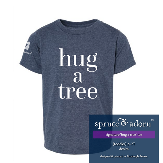 navy description box, overlying denim colored oversized signature ‘hug a tree’ @spruceandadorn hoodie reading : ‘hug a tree’ (unisex • toddler) 2T-7T with our logo on the right arm patch + imprinted highlighter green label reading : heart shape, spruce & adorn™, life styled with intention™, imprinted label reading : designed & printed in Pittsburgh, Pa